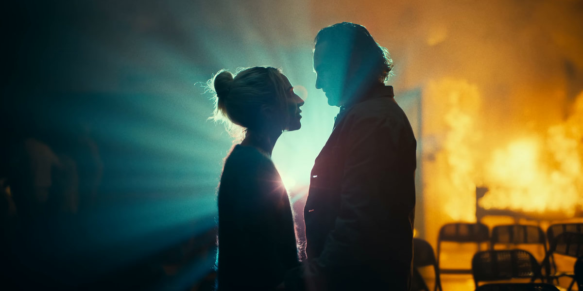 two people, fire, chairs, stage light, smoke, intense, dramatic, romantic, chaotic, passionate, gazing, standing, interacting