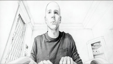 low-angle medium-close-up 1-person looking-at-camera upper-body interior room window metal-grate bookshelf framed-pictures textured-ceiling warm-light dark-shirt hands-visible